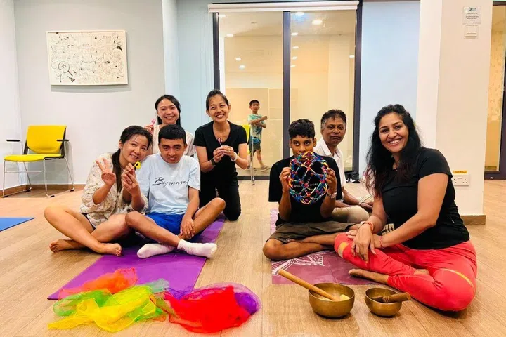Participants alongside their caregivers during an inclusive yoga session at the Enabling Village with BlissYogaSG founder Parul Chaturvedi (right).