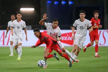 Singapore’s Akram Azman (in red) and Hong Kong’s Walter Soares Junior during the AFC Asian Cup 2027 qualifier at the National Stadium on March 25.