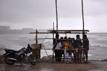 People gather as they take cover under a makeshift shelter from heavy rain during Cyclone Michaung, at Kasimedu Beach, in Chennai, India, 02 December 2023.