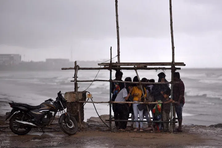 People gather as they take cover under a makeshift shelter from heavy rain during Cyclone Michaung, at Kasimedu Beach, in Chennai, India, 02 December 2023.