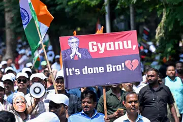 A protester carries a placard next to India's national flag during a demonstration calling for the resignation the country's Chief Election Commissioner Gyanesh Kumar over alleged irregularities in the Special Intensive Revision (SIR) of electoral rolls, in Mumbai on October 4, 2026.