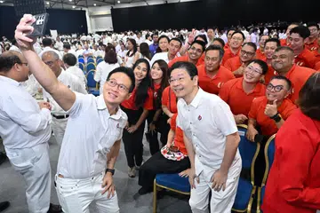 தற்காப்பு துணை அமைச்சர் டெஸ்மண்ட் சூ, மசெக தலைமைச் செயலாளர் லாரன்ஸ் வோங், தொழிற்சங்க உறுப்பினர்களுடன் புகைப்படம் எடுத்துக்கொள்கின்றனர்.