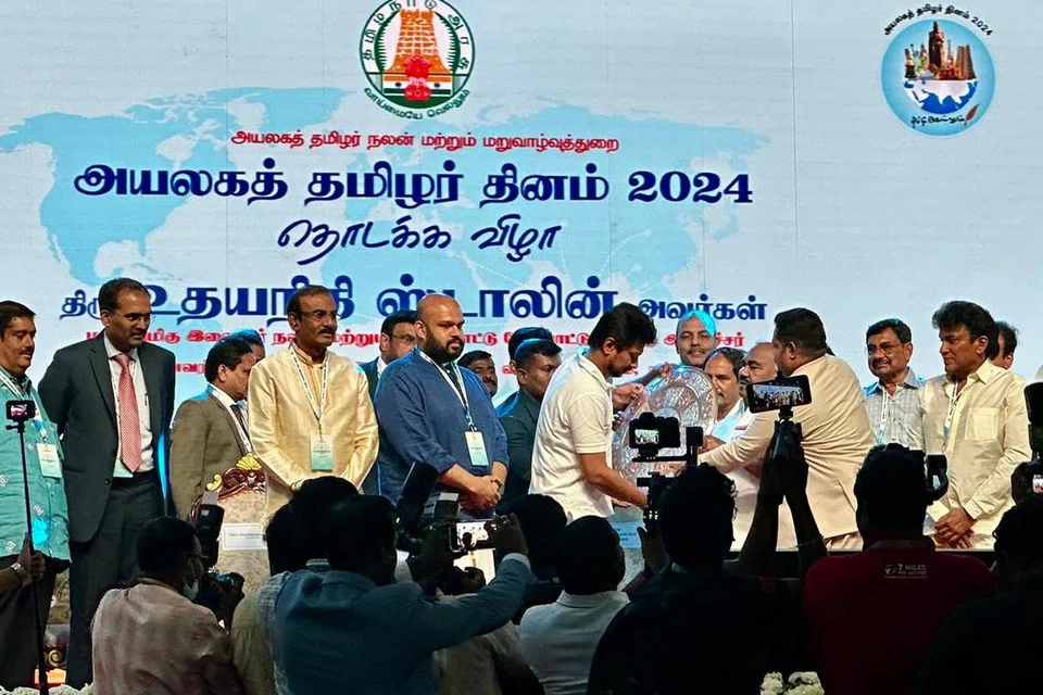 அயலகத் தமிழர் தின விழா மேடையில் தமிழகத் துணை முதல்வர் உதயநிதி ஸ்டாலின், பிற பேராளர்களுடன் இரா. தினகரன் (இடக்கோடி).