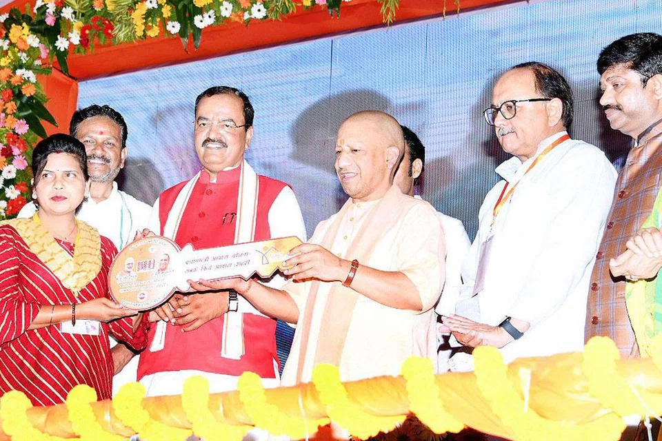 வீடு வழங்கும் நிகழ்ச்சியில் வீட்டுச் சாவியை வழங்கும் யோகி ஆதித்யநாத்.