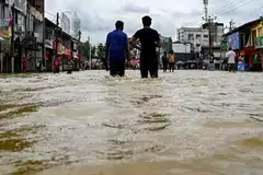 முழங்கால் அளவு வெள்ளத்தில் மக்கள் நடந்து செல்கின்றனர். 