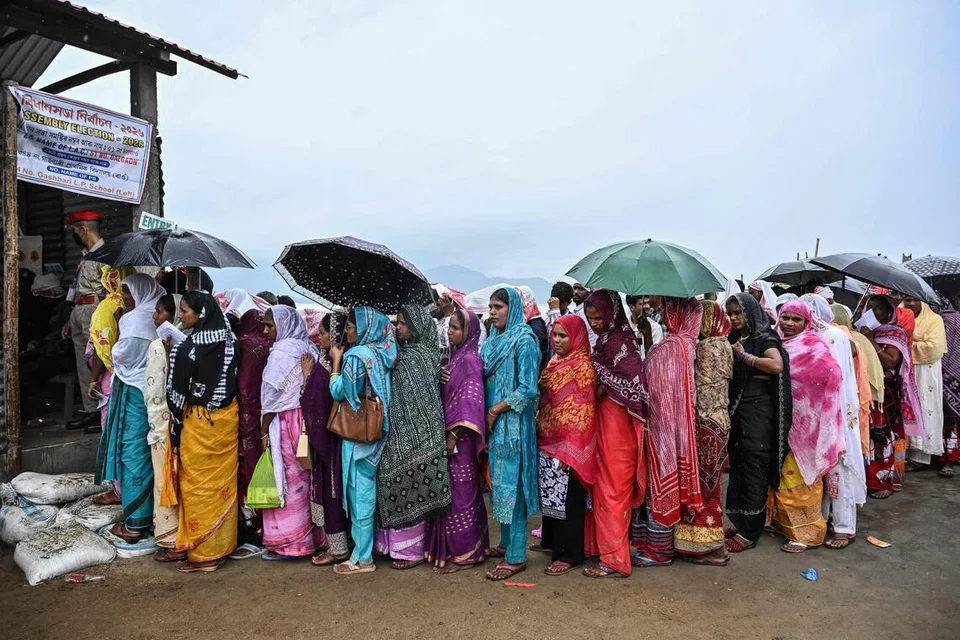 மழையைப் பொருட்படுத்தாது வாக்களிக்க வரிசையில் காத்திருந்த அசாம் மாநில வாக்காளர்கள்.