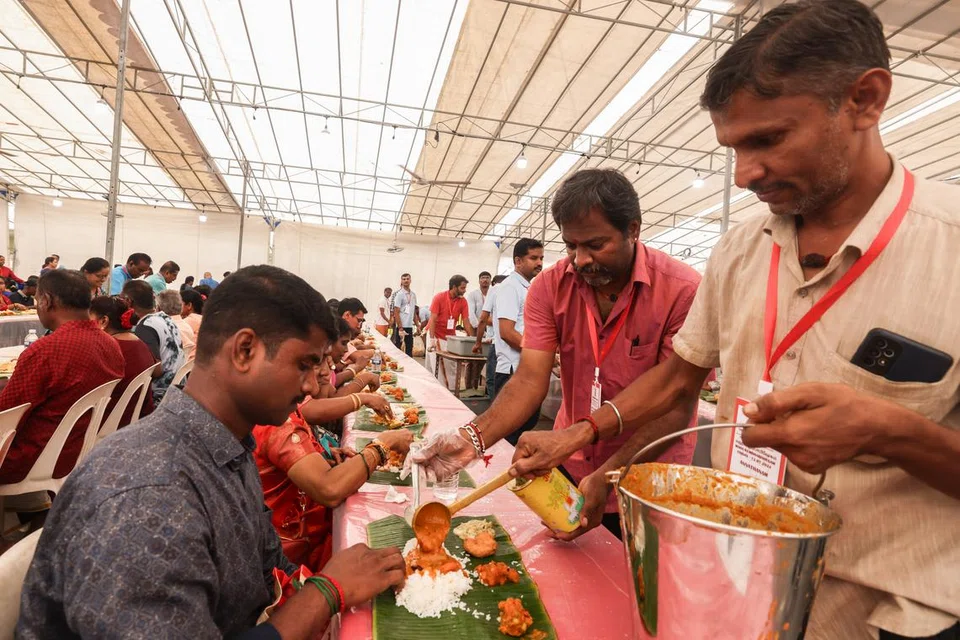 மக்களுக்கு உணவு பரிமாறும் ஆலயத் தொண்டூழியர்கள்.
