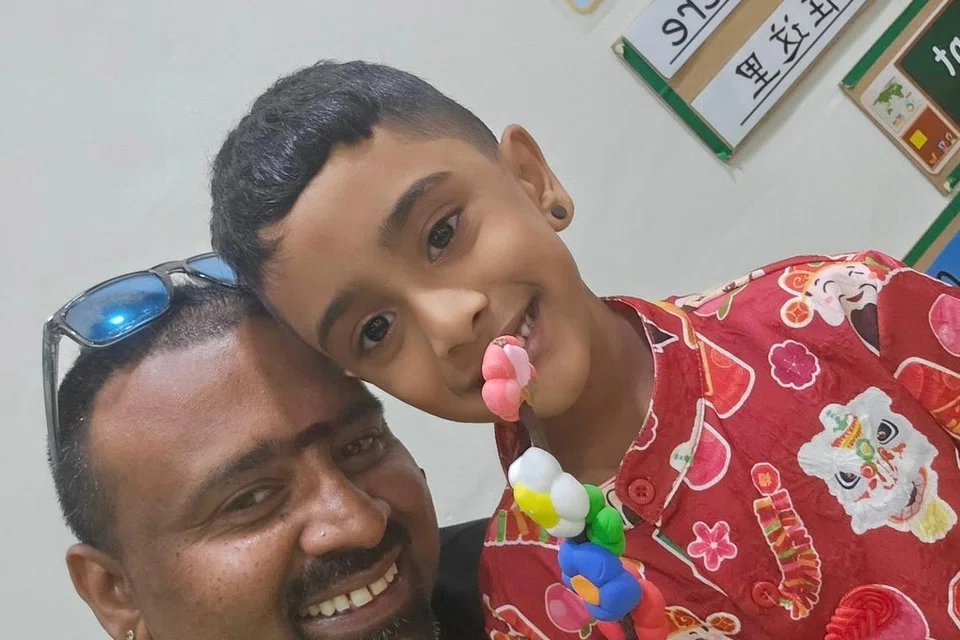 ஐந்து வயது சைலேஷ், தாம் செய்திருந்தக் கைவினைப் பொருளைக் கையில் பிடித்துகொண்டு தந்தையுடனு படமெடுக்கிறார்.