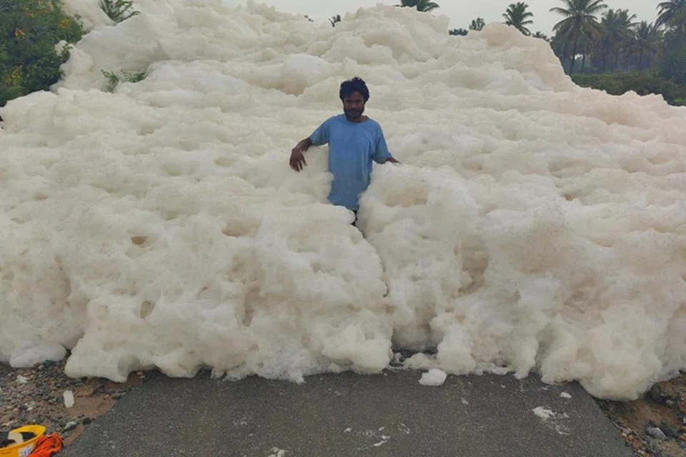 தண்ணீரும் ரசாயனக் கழிவும் கலந்த வெள்ளை நுரை பாலத்தை மூடிவிட்டது. அந்த நுரையில் ஒருவர் நின்றுகொண்டு இருக்கிறார். 