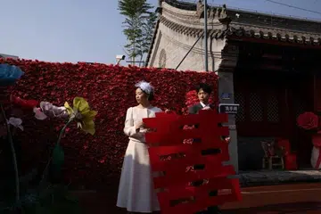 சீனக் கோயில் முன்பாக திருமணப் படம் எடுத்துக்கொள்ளும் தம்பதி.