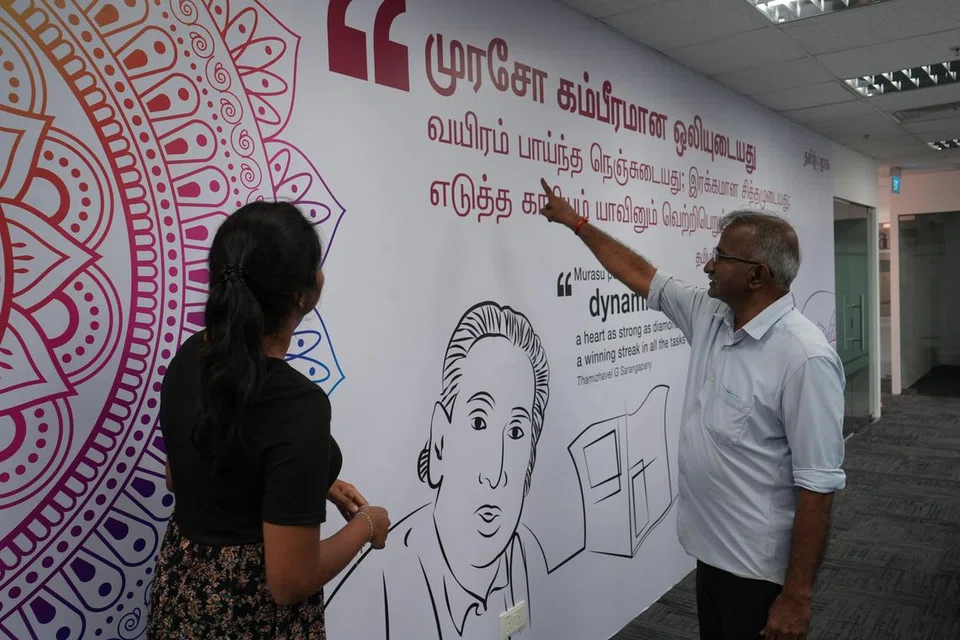 புதிய அலுவலகத்தில் சுவர் சித்திரத்தைக் குறித்து இளம் செய்தியாளர் அனுஷா செல்வமணியிடம் விளக்கம் அளிக்கிறார் தமிழ் முரசின் மூத்த உதவி ஆசிரியர் திரு குணாளன்.
