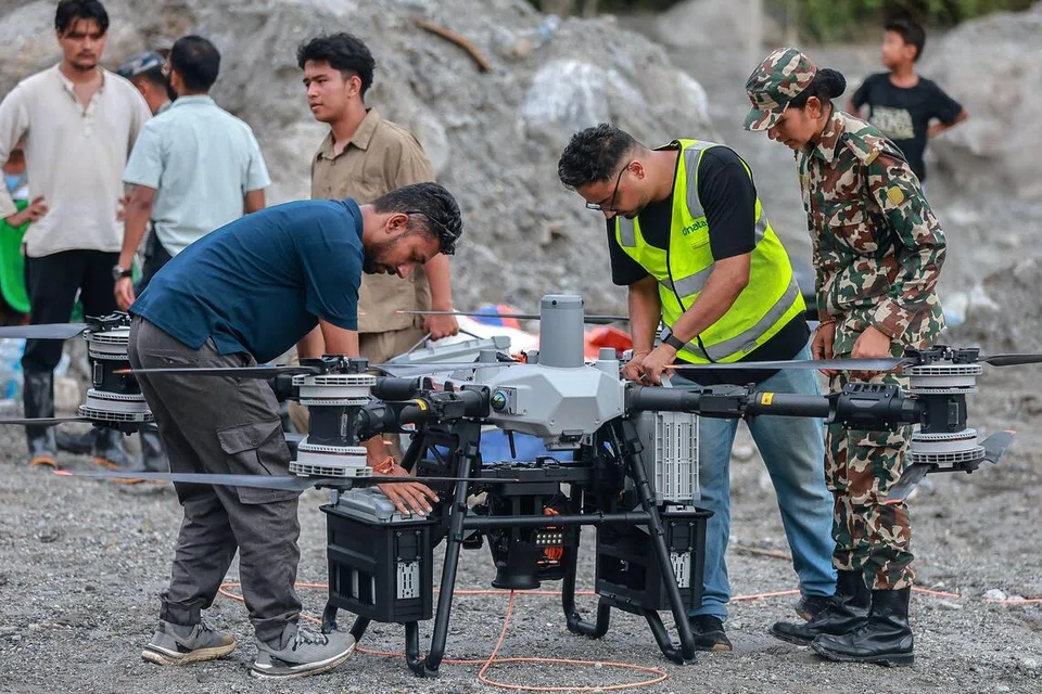 நேப்பாளத்தில் வெள்ளத்தால் பாதிக்கப்பட்ட திரிசூலி பகுதியில் ஆளில்லா விமானம் மூலமாக உதவிப் பொருள்களை அனுப்பி வைக்கும் பணியில் ஈடுபட்டுள்ள தொழில்நுட்பர்கள்.