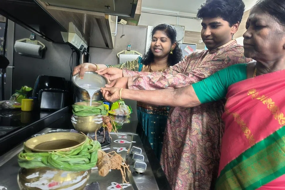 (இடமிருந்து) சண்முகம் தமிழ்ச்செல்வி, கணேசன் கவின்,  சண்முகம் நீலா ஆகியோர் மஞ்சள் கொத்து சுற்றப்பட்ட பொங்கல் பானையில் பால் ஊற்றி தைத்திருநாளை வரவேற்கின்றனர். 