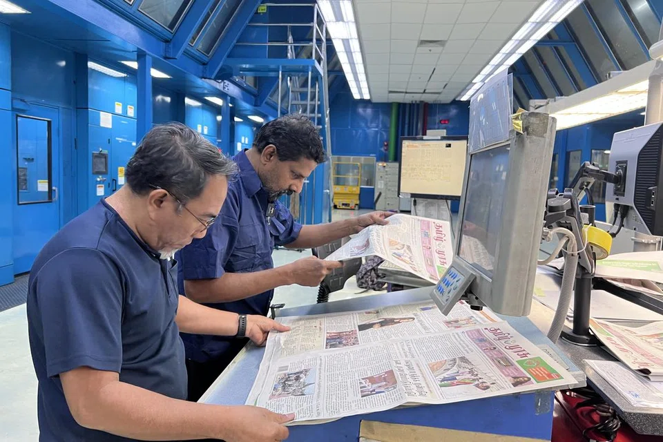 அச்சிடப்பட்ட செய்தித்தாளை சரிபார்க்கும் அச்சுக்கூட ஊழியர்கள். 