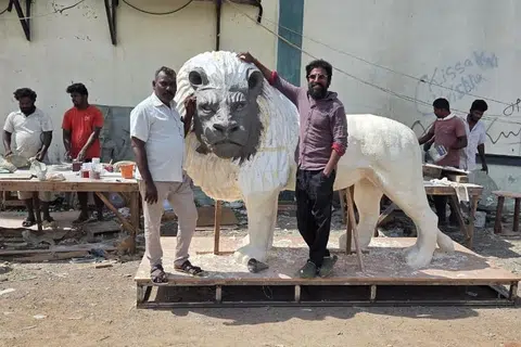 தமது சிங்கச் சிற்பத்துடன் திரு குணசேகரன் (வலம்).