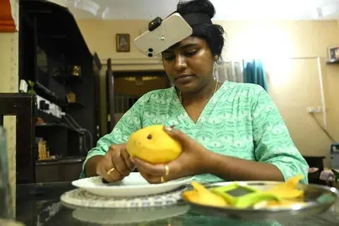 இயந்திர மனிதர்களுக்கு பயிற்சி அளிக்க, வீட்டில் மாம்பழம் நறுக்குவதைக் காணொளியாகப் பதிவுசெய்யும் சென்னையைச் சேர்ந்த இல்லத்தரசி நாகிரெட்டி ஸ்ரீரம்யசந்திரா.