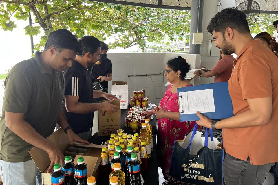 மக்களுக்கு உணவு, வீட்டுப் பொருள்களை விநியோகிக்கும் பிஎஸ்ஏ கிரெசண்ட் சிங்கப்பூர் முன்னாள் மாணவர் சங்க உறுப்பினர்கள். படத்தில், பொருள்களைத் தேர்ந்தெடுக்கும் 65 வயது பிரேமா (பின்னால்).
