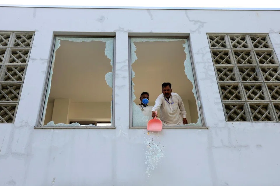 தீ அணைக்கப்பட்ட பிறகு உடைந்த சன்னல் கண்ணாடிகளை அகற்றும் ஊழியர்கள்.