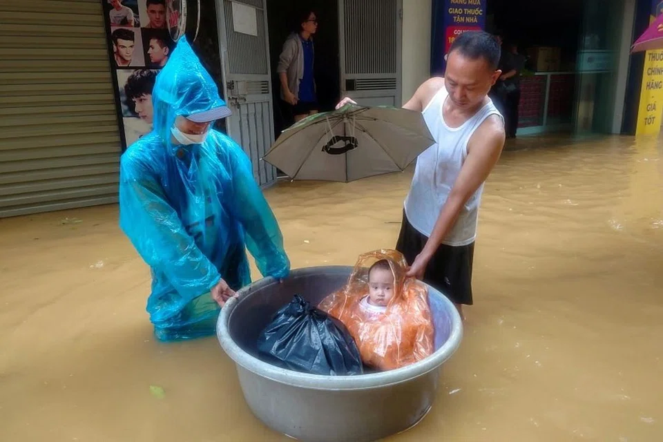 செப்டம்பர் 11ஆம் தேதி, ஹனோயில் வெள்ளம் நிறைந்த வீதியில் சிறுவனைப் பாதுகாப்பாக அழைத்துச் செல்லும் காட்சி. 
