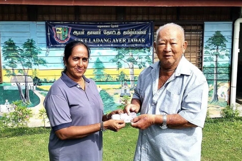 பள்ளிப் பிரதிநிதி ஒருவரிடம் நன்கொடை வழங்கும் சீன ரப்பர் வணிகர் யெக் டோங் பிங்.