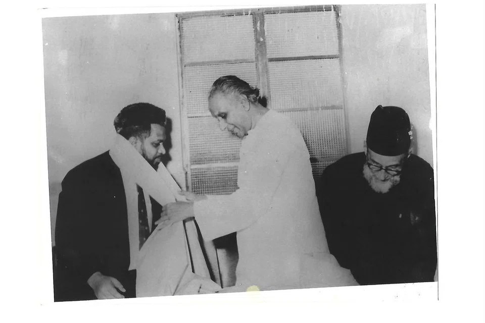 தமிழ் முரசு நிறுவனர் தமிழவேள் கோ.சாரங்கபாணி, சிராஜுல் மில்லத்துக்குப் பொன்னாடை அணிவித்து சிறப்பு செய்கிறார். அருகில் காயிதெ மில்லத் அப்துஸ் ஸமது.