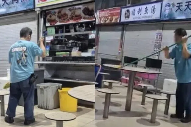 உணவங்காடி மேசை நாற்காலிகளைத் துடைப்பம் கொண்டு சுத்தம் செய்த ஆடவர்