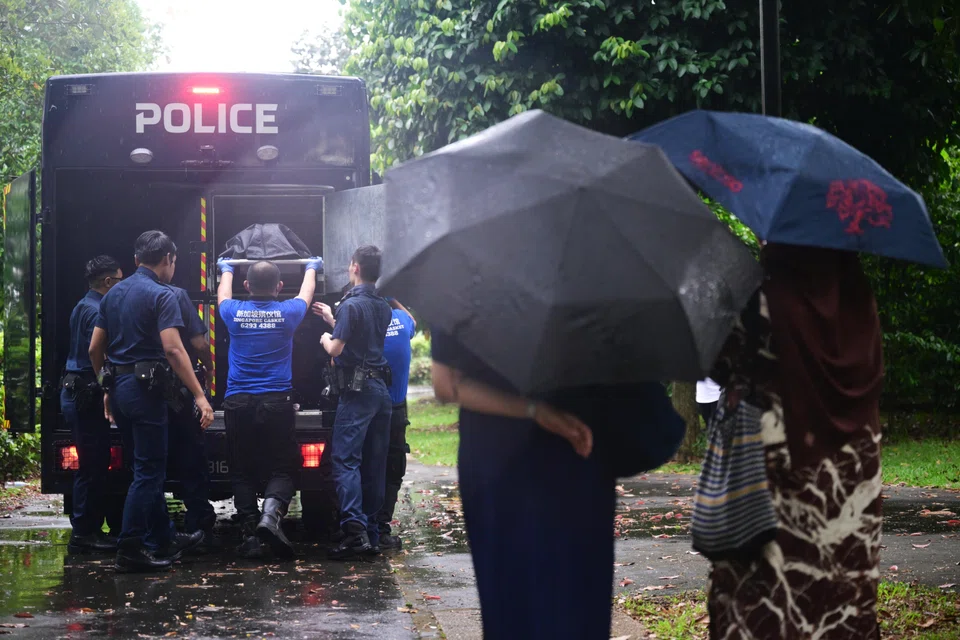 காவல்துறை சவ ஊர்திக்குள் ஆடவரின் சடலத்தை அதிகாரிகள் வைப்பதைப் பார்க்கும் குடும்ப உறுப்பினர்கள்.