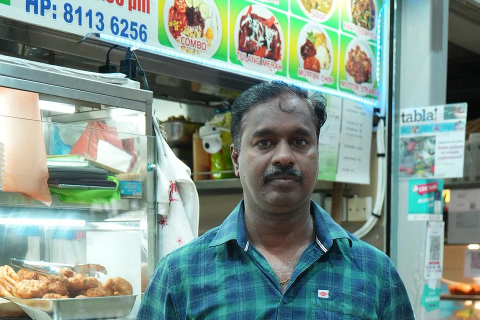 ஆட்குறைப்பால் பாதிக்கப்பட்ட ஊழியர் பழனி பாண்டி, இன்று உணவங்காடி நிலையத்தில் இந்திய உணவுக் கடை முதலாளியாக இருக்கிறார்.