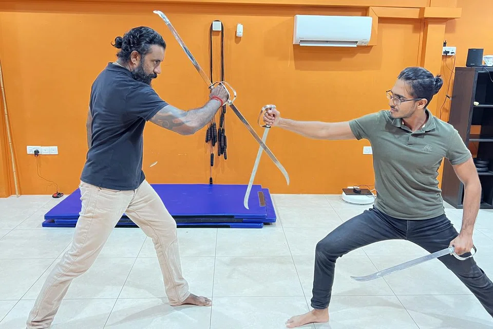 சிவனாக நடிக்கும் வேதகிரி கோவிந்தசாமி (இடம்), பார்கவ ராமராக நடிக்கும் இ.ரூபன், வாள் சண்டைப் புரியும் காட்சி. இருவரும் இந்நாடகத்தை அரங்கேற்றும் களரி அகேடமியின் இணை நிறுவனர்கள்.