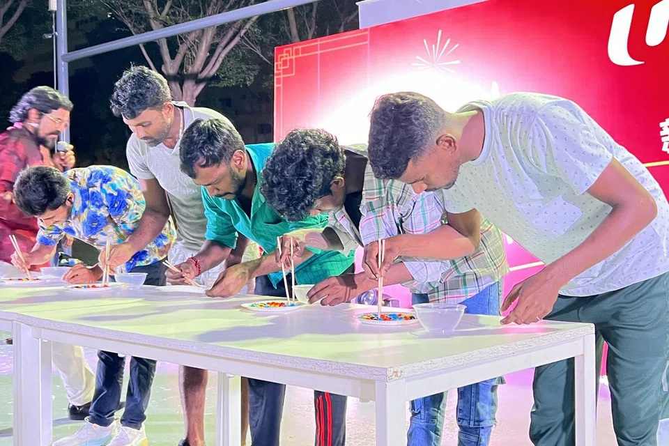 சீன வழக்கப்படி குச்சிகளைப் பயன்படுத்தும் விளையாட்டில் ஈடுபடும் வெளிநாட்டு ஊழியர்கள்.