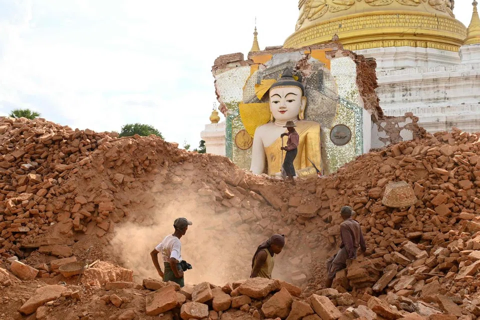 மியன்மாரில் நிலநடுக்கத்தால் பாதிக்கப்பட் பகுதி ஒன்றில் சேதமடைந்த புத்தர் சிலைக்கு அருகே உள்ள சிதைவுகளை அகற்றும் மக்கள்.