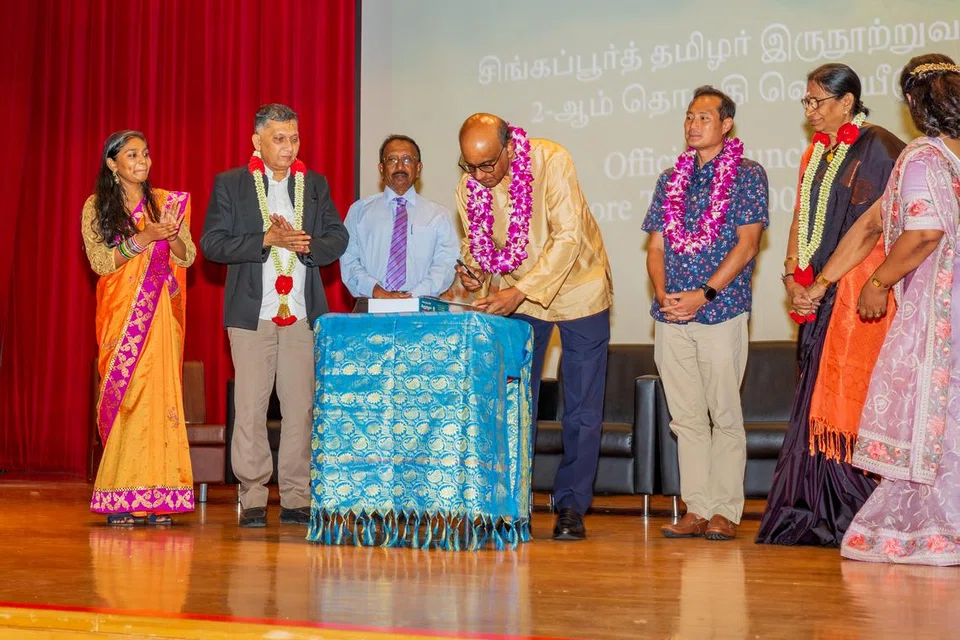 நூலில் கையெழுத்திடும் முன்னாள் மூத்த அமைச்சர் தர்மன் சண்முகரத்தினம்.