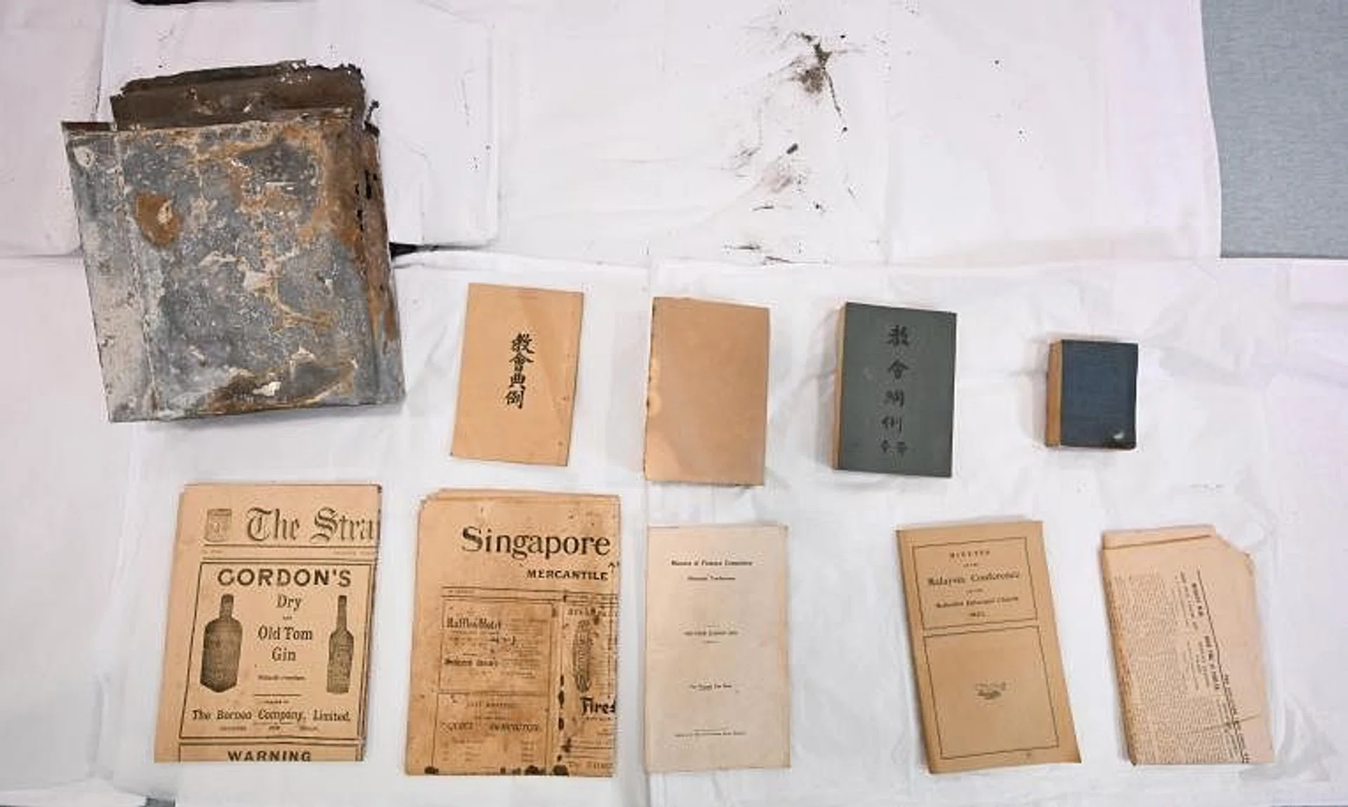 The steel capsule (top left) alongside artefacts that were found in it, including a copy of The Straits Times dated Jan 8, 1924.