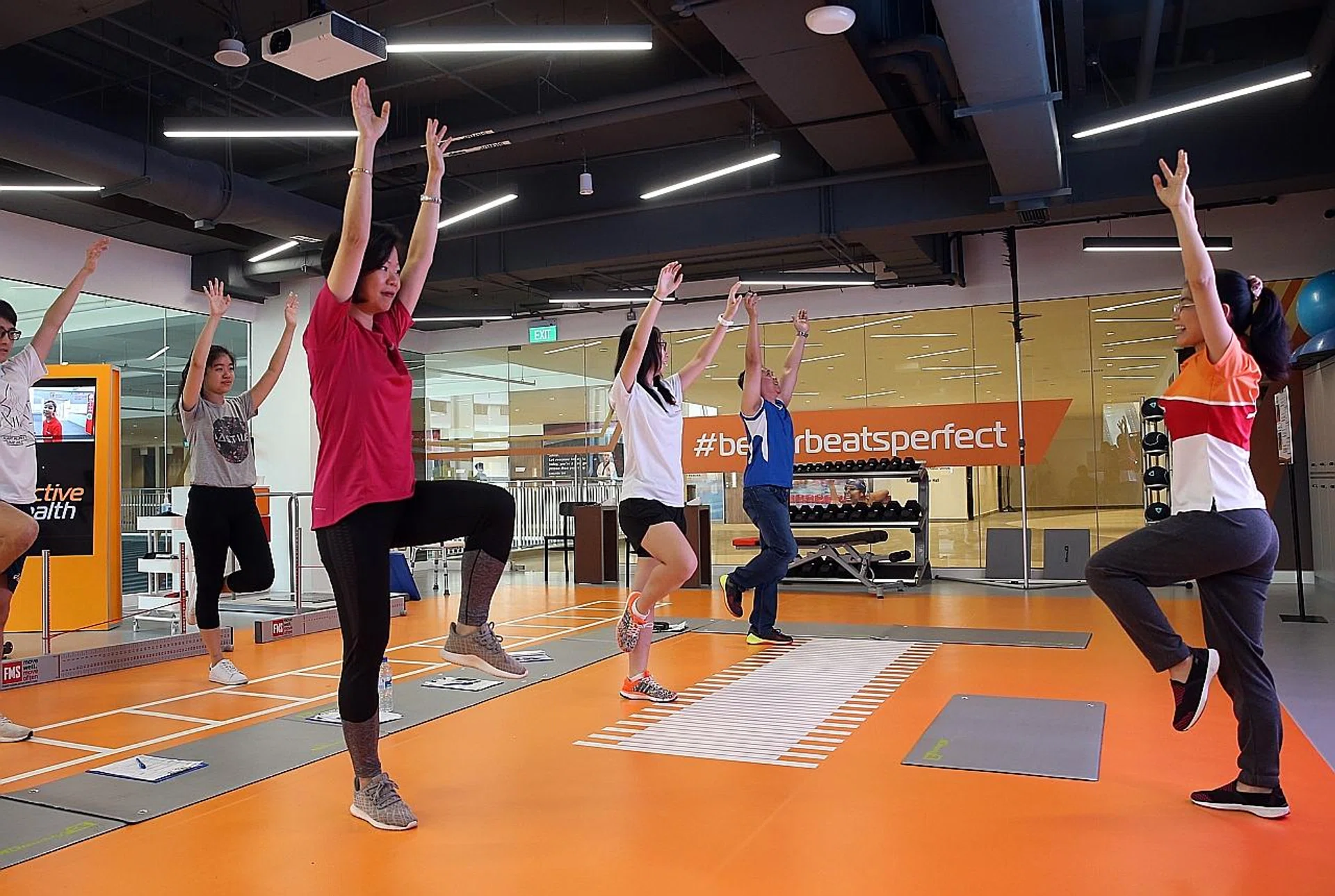 Ms Sim Ann (left) and journalists trying out some exercises at Heartbeat@Bedok Active Health Lab. 