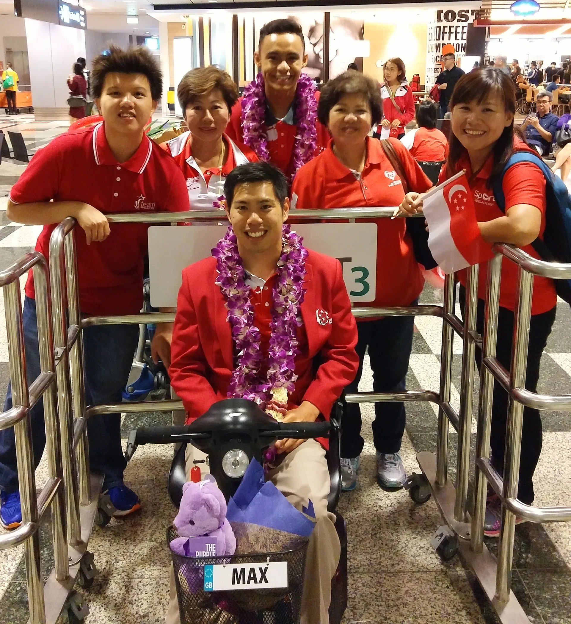 SUPPORT: Tan and fellow para-athlete Suhairi Suhani (standing, with garland) and their friends at the airport yesterday.