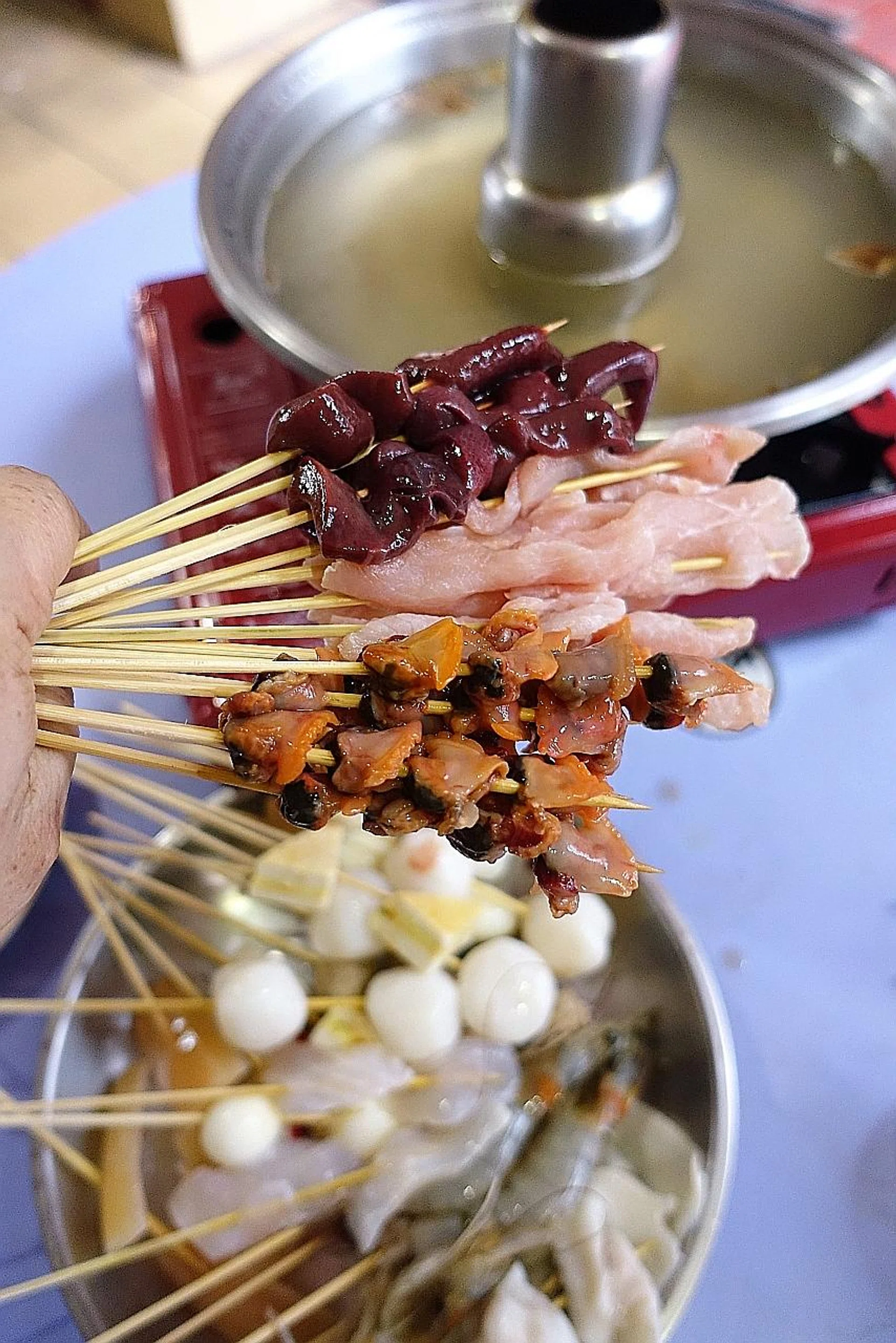 Mr Hay Choo Seng and his wife hand-skewer the ingredients (above).