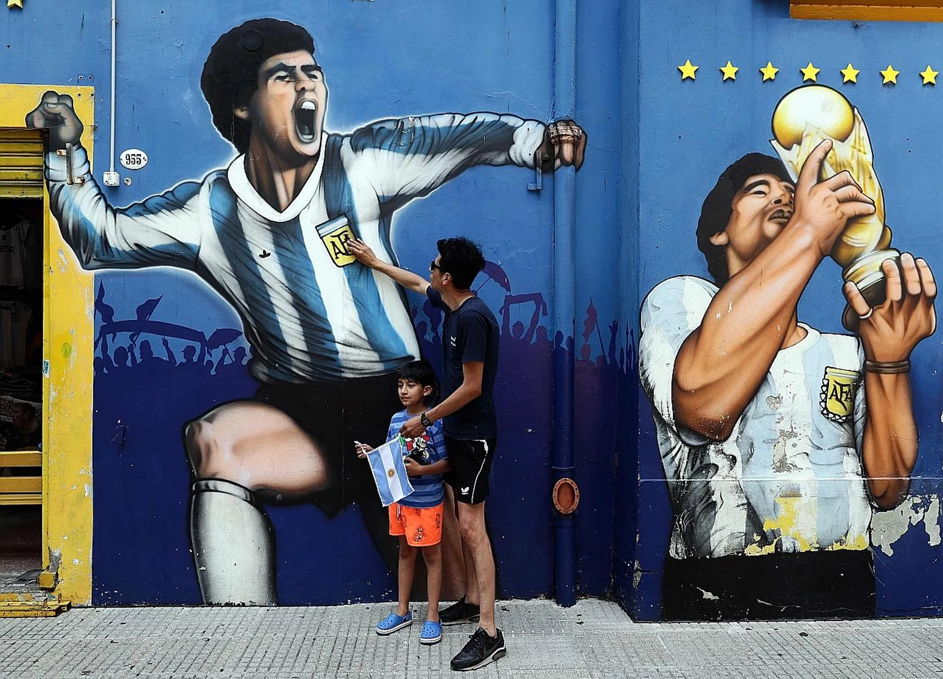 (Above) Fans paying tribute to Argentinian football legend Diego Maradona next to a mural in Buenos Aires.
