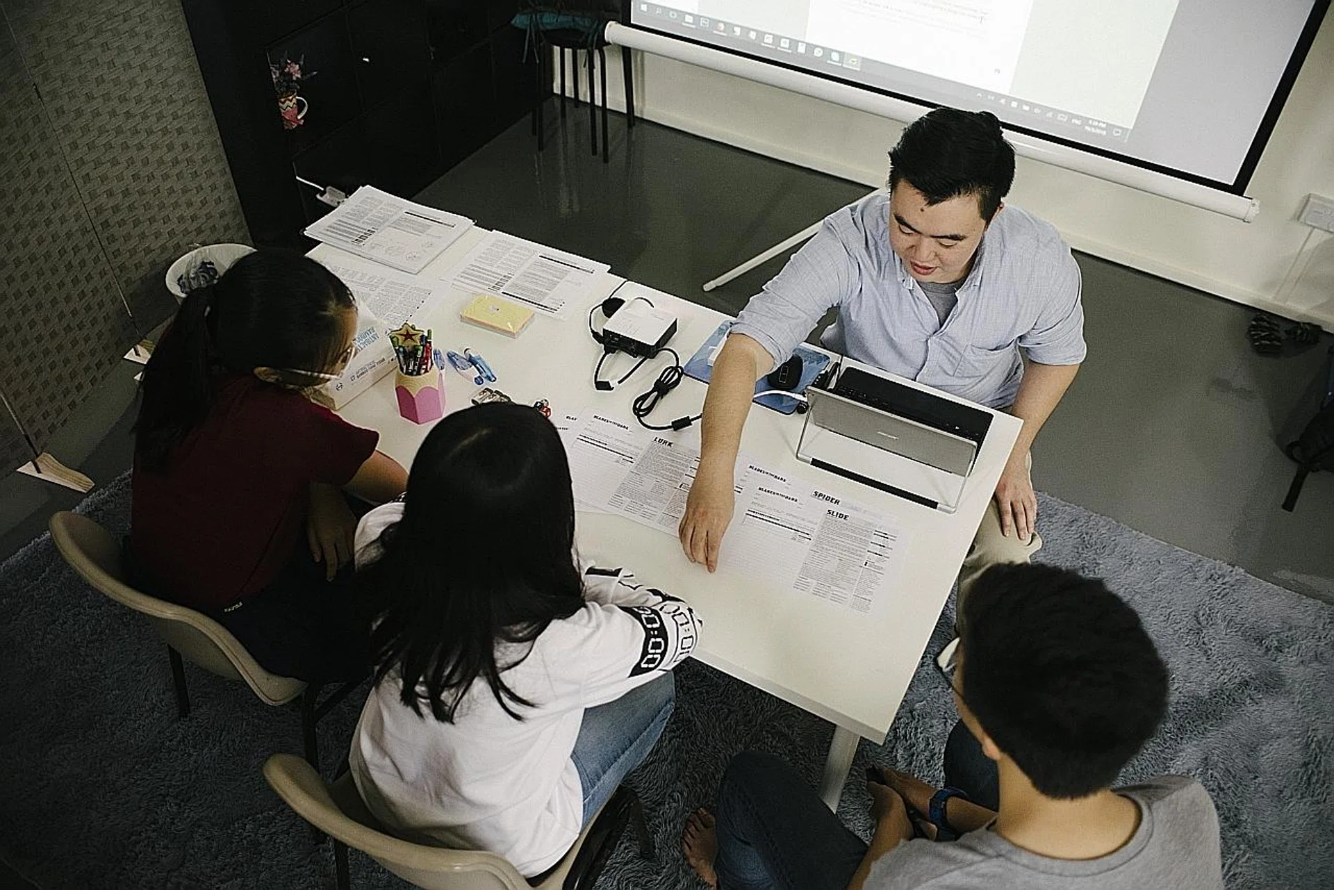 Mr Shaun Low playing a board game with some of his students. 