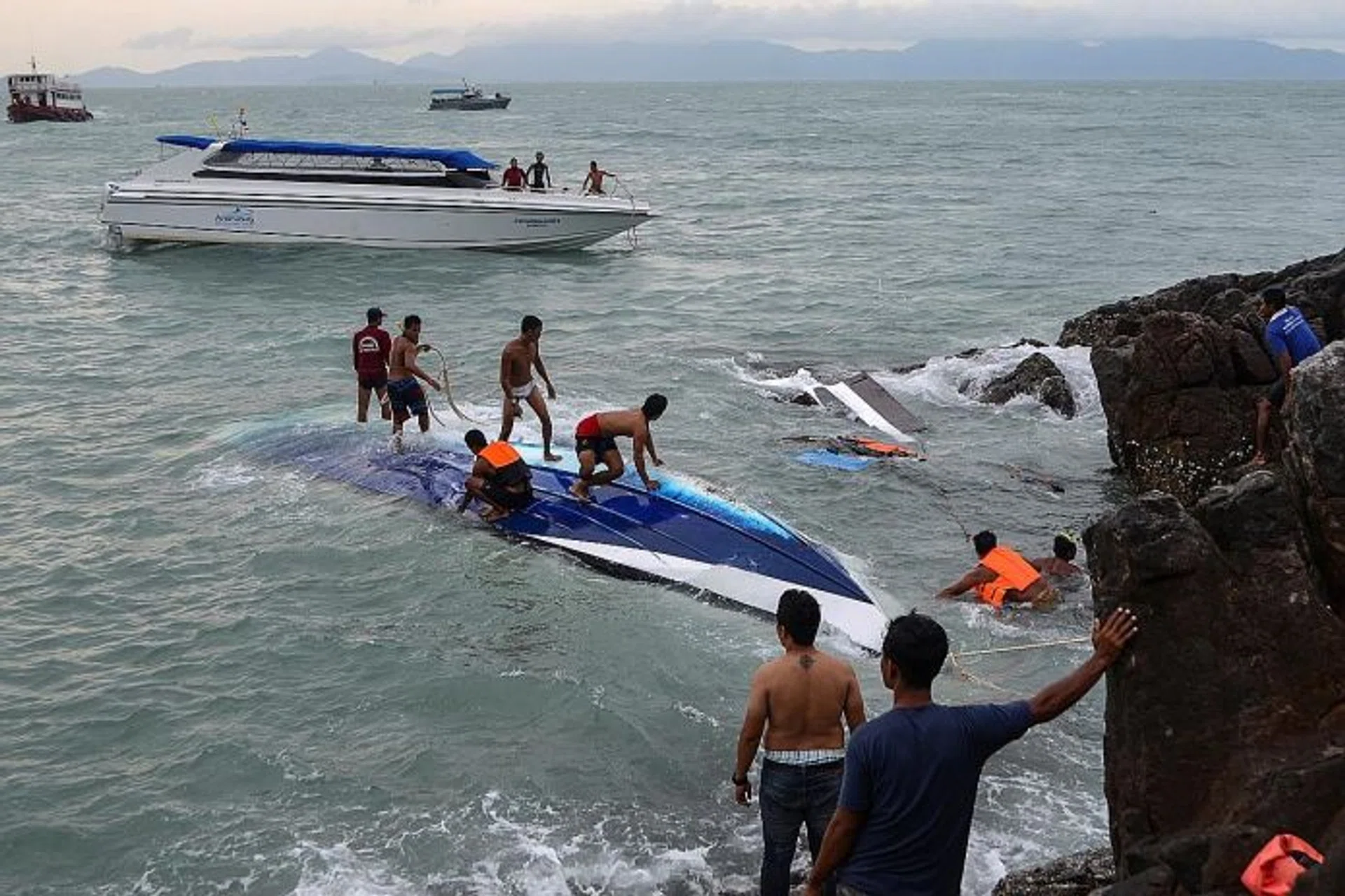 OVERTURNED: Rescue workers search for victims after the crash. One British man is still missing.