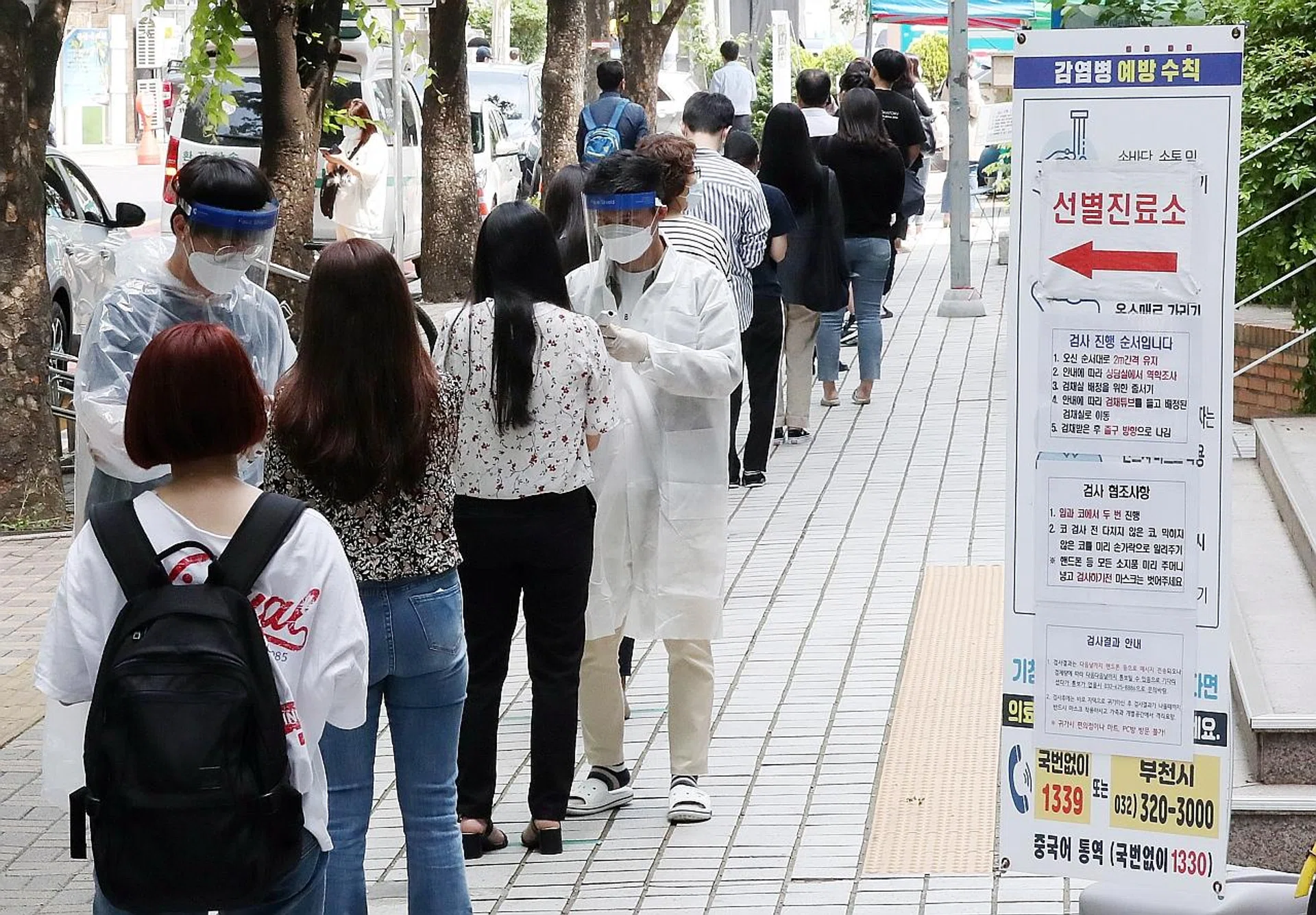 People wait in line to be tested for coronavirus at an outdoor clinic in Bucheon, where there was an outbreak at a warehouse of an e-commerce firm. 