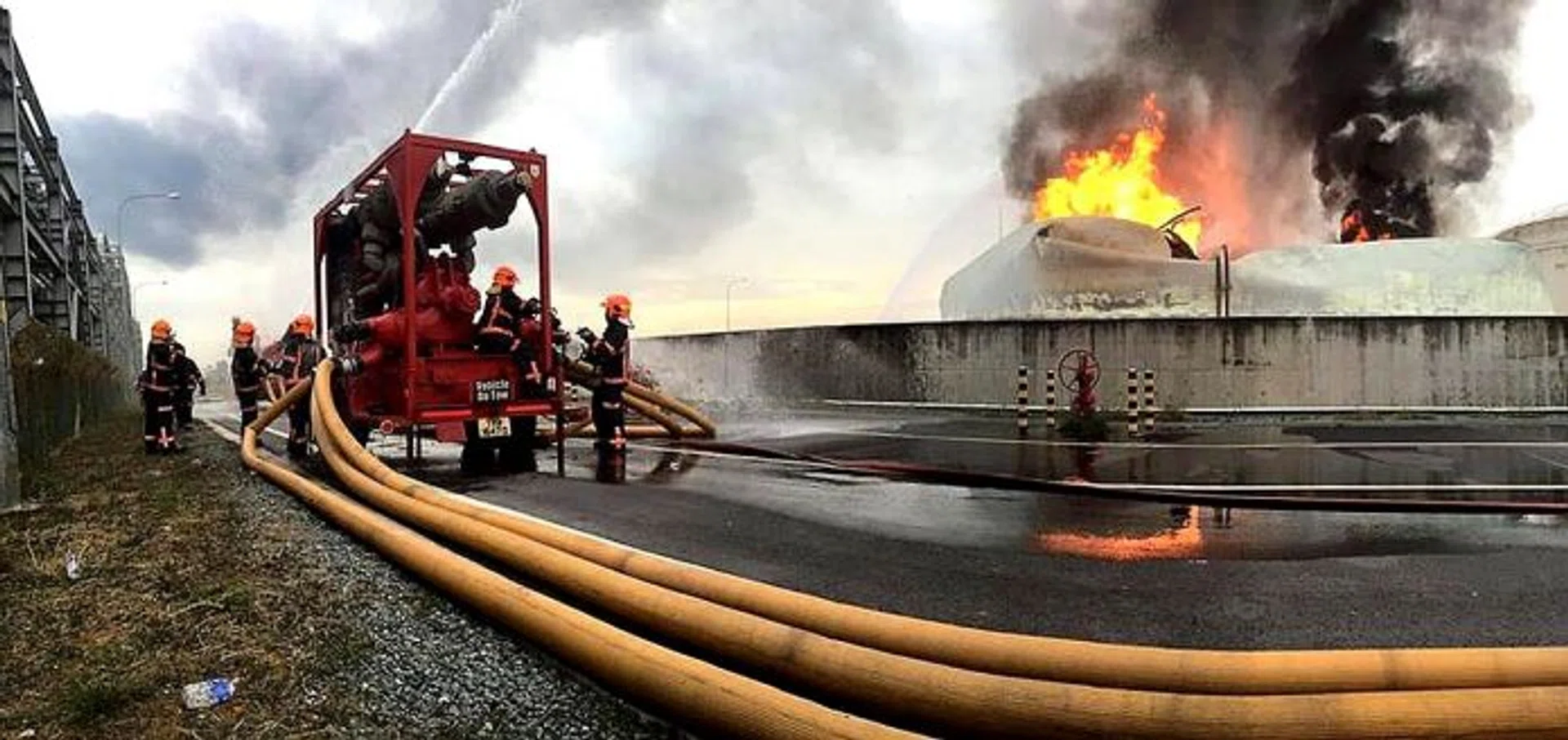 FIERY: (Above) SCDF fighting the fire. The plume of black smoke could be seen from about 2km away.