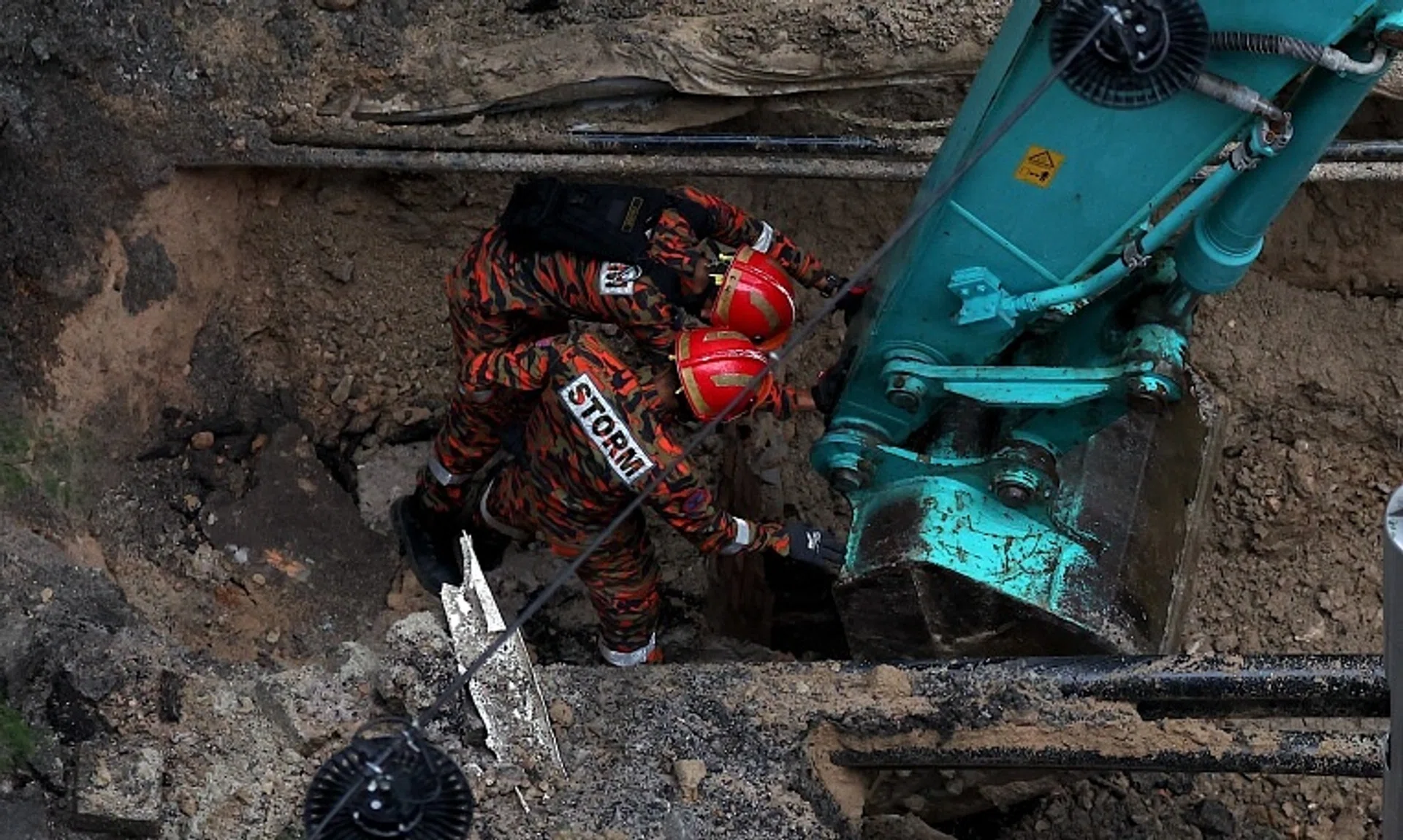 Malaysia Fire and Rescue Department officers inspecting the site where a woman fell into a sinkhole in Jalan Masjid India on Aug 23.