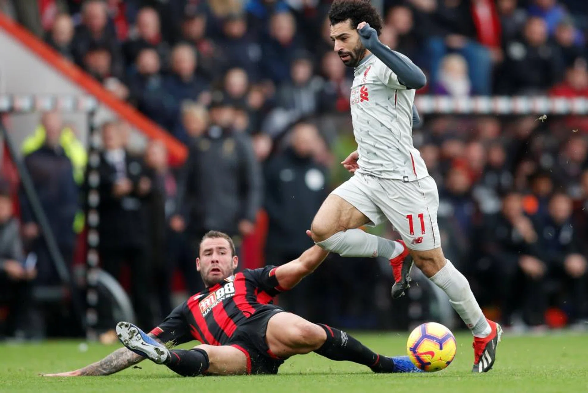 Liverpool's Mohamed Salah surging forward as Bournemouth's Steve Cook attempts to stop him.