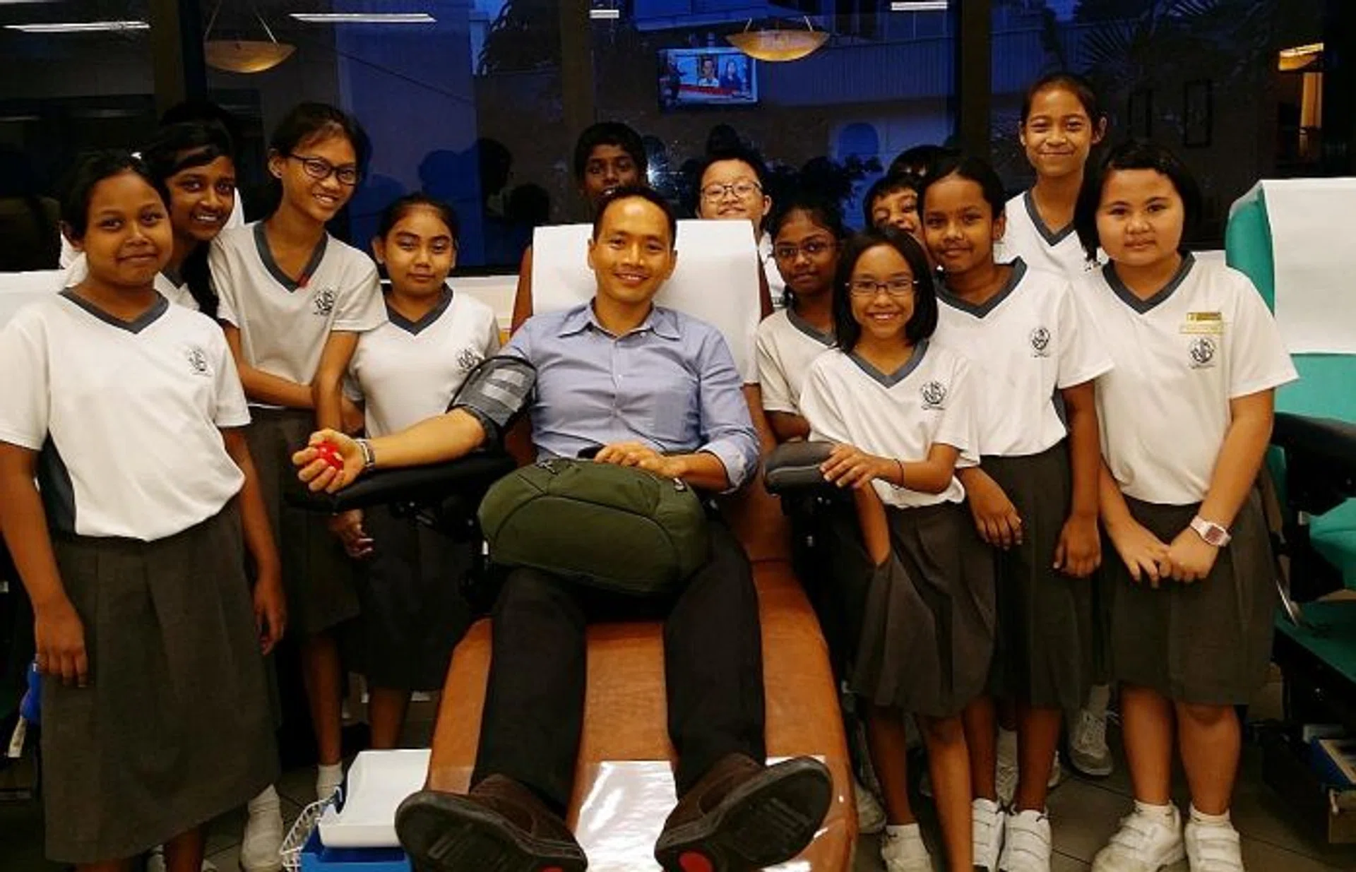 AWARDED: Mr Koh Wee Jin Algene donating blood while primary school pupils look on. 