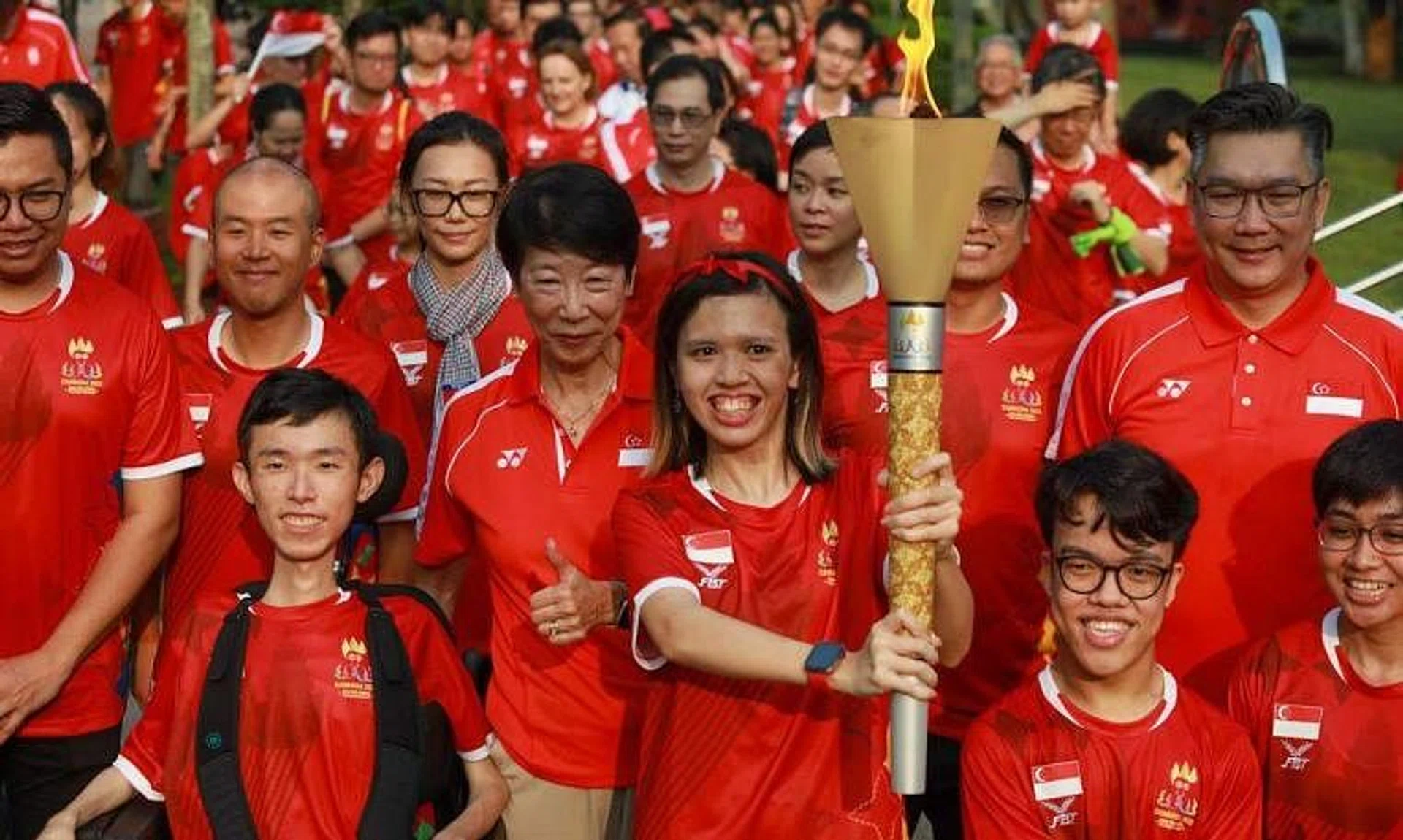 Para athlete Maisarah Mohamed Hassan (centre) carrying the torch during the SEA Games and Asean Para Games torch relay in Singapore on April 15, 2023.