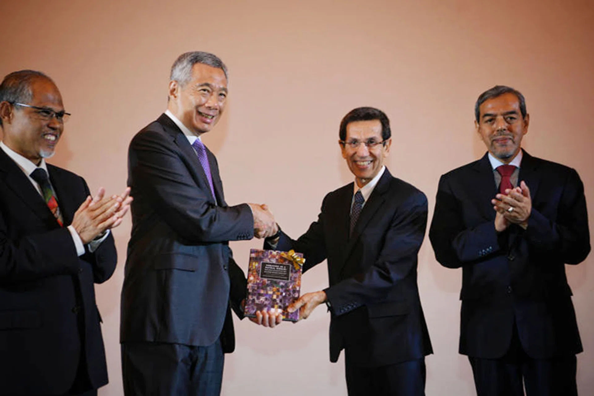 Prime Minister Lee Hsien Loong receiving a copy of the book Thriving In A Plural World: Principles And Values Of The Singapore Muslim Community from Muis president Mohammad Alami Musa at the conference to mark Muis’ 50th anniversary on Wednesday. With them were Minister-in-charge of Muslim Affairs Masagos Zulkifli (far left) and Muis CEO Abdul Razak Hassan Maricar.