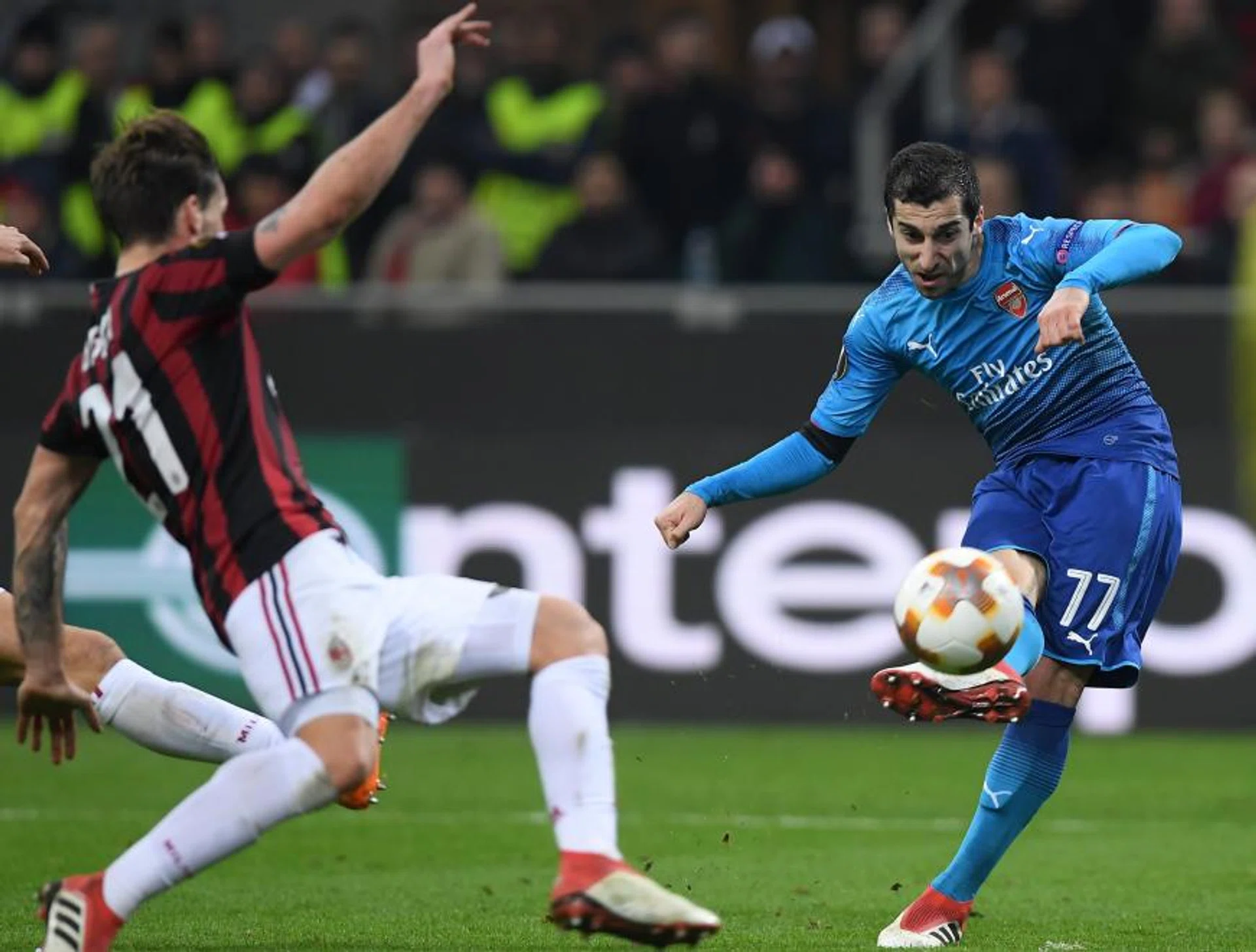 Arsenal's Henrikh Mkhitaryan shooting at goal as AC Milan's Lucas Biglia closes in.