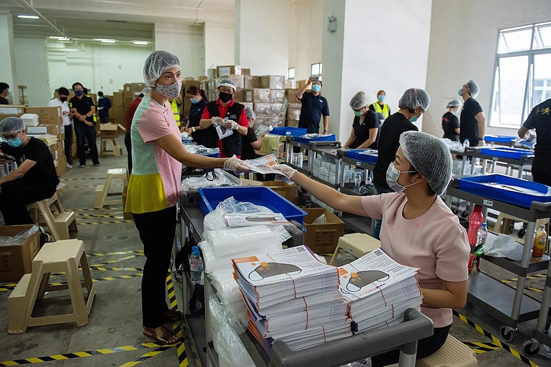 Manpower Minister Josephine Teo and Senior Minister of State for Culture, Community and Youth Sim Ann (seated) packing mask kits last Saturday for migrant workers. 