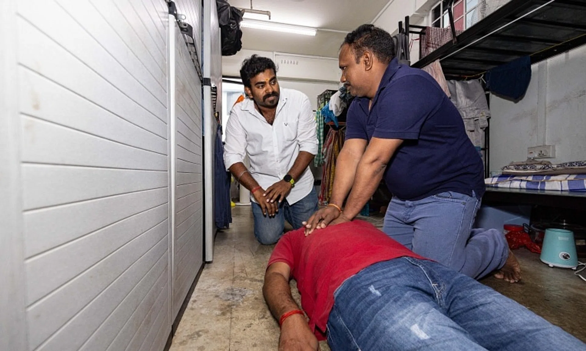 (From left) Mr Karunanithi Prabhakaran guiding Mr Ganapathi Kaliyamoorthy on how to perform cardiopulmonary resuscitation on Mr Mohan Satheesh Kumar in a demonstration.