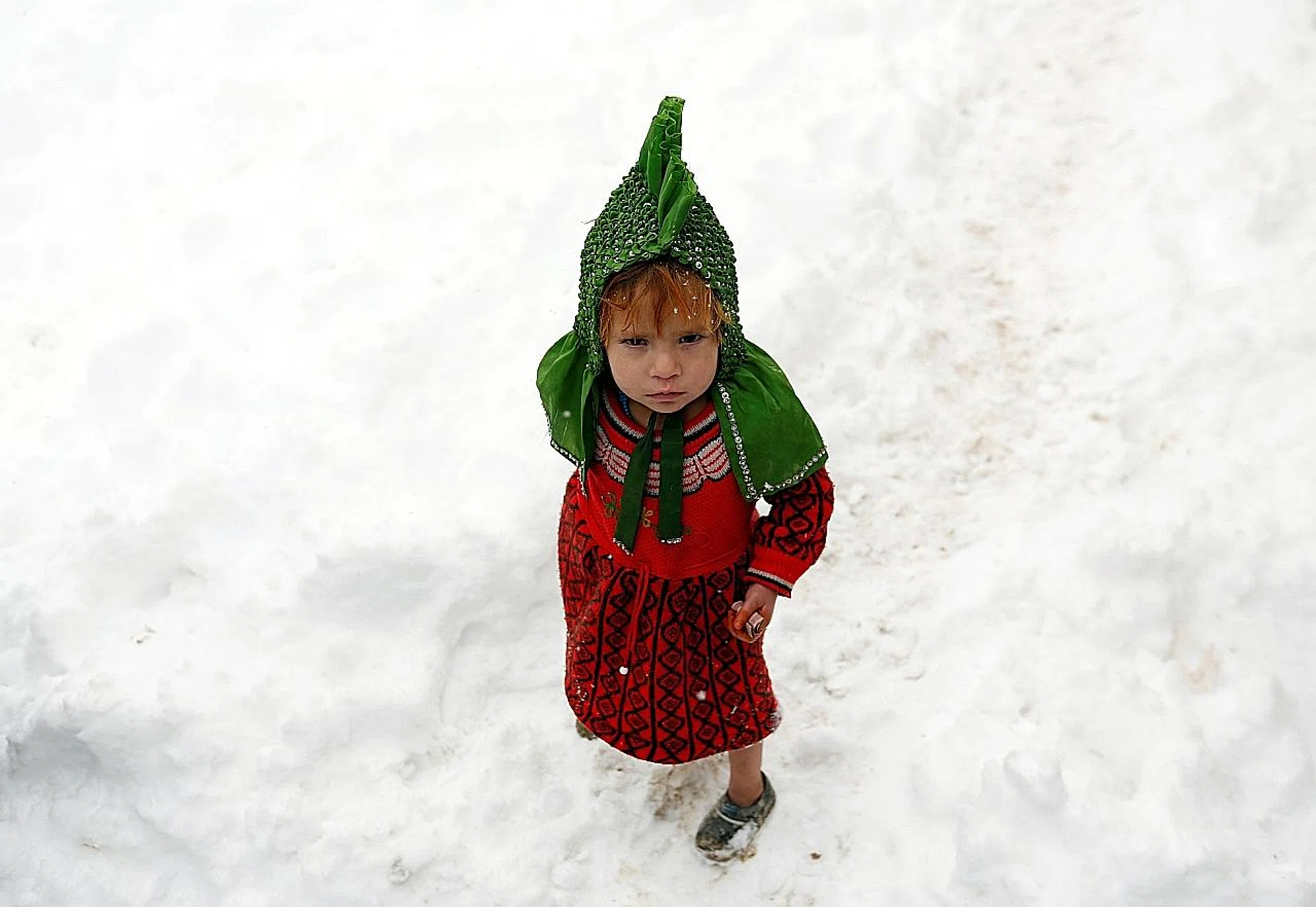 A displaced Afghan child stands outside her shelter in Kabul.